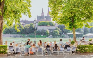 Am Basler Rheinufer zeigt sich, weshalb Städtereisen im eigenen Land gefragt bleiben: Gäste geniessen Gastronomie am Wasser, kurze Wege und urbane Lebensfreude.