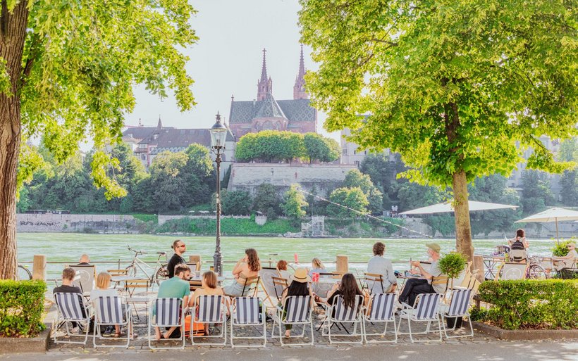 Am Basler Rheinufer zeigt sich, weshalb Städtereisen im eigenen Land gefragt bleiben: Gäste geniessen Gastronomie am Wasser, kurze Wege und urbane Lebensfreude.