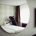 Person arbeitet in einem Hotelzimmer und deckt das Bett