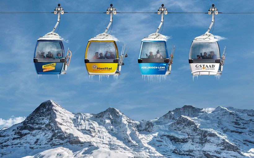 Symbolbild: vier Gondeln von vier Skigebieten vor Eiger, Mönch und Jungfrau-Massiv