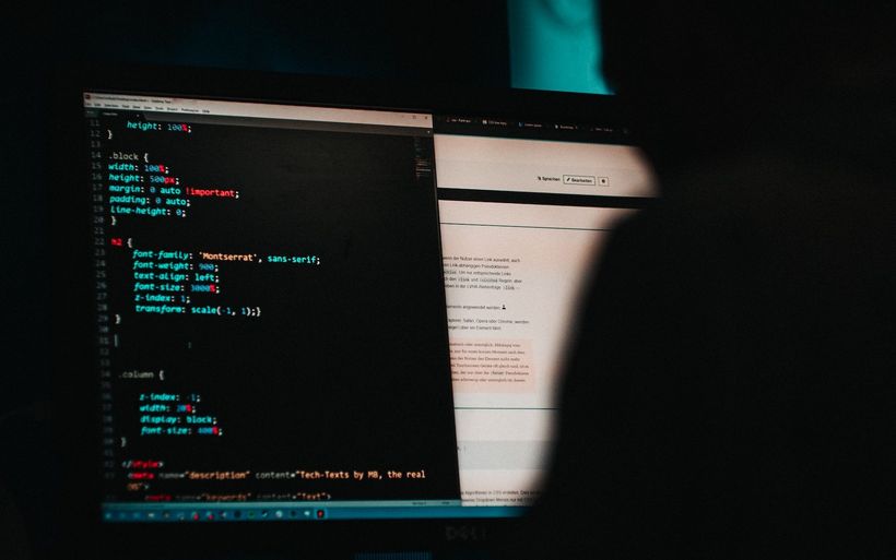Hackerangriff, Person sitzt an einem Computer und arbeitet an einem Code