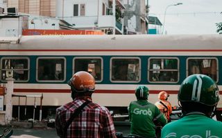 Normalität Asien: Essenslieferung via Grab-Roller vor einem Bahnübergang in Hanoi.