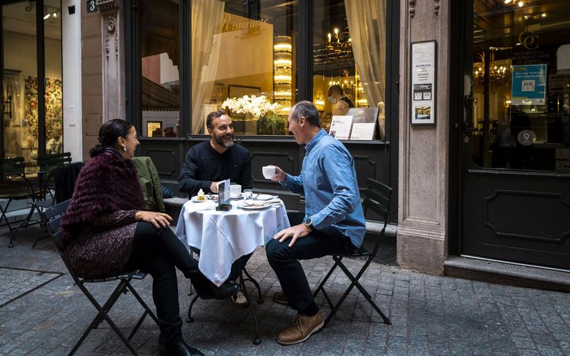 Italienische Touristen sitzen in Lugano vor einem Café.