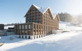 Die 2022 eröffnete Stoos Lodge besticht durch ihre durchgehende Holzfassade. Dank ihr fügt sich das Gebäude ideal ins Ortsbild ein.