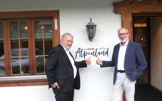 Bild von zwei Personen vor dem Schild vom Hotel Alpenland