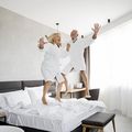 Ein Mann und eine Frau hüpfen freudig auf einem Bett