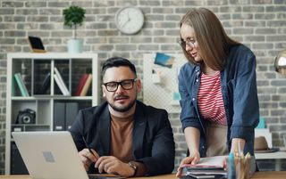 Symbolbild zwei Menschen unterhalten sich vor dem Laptop